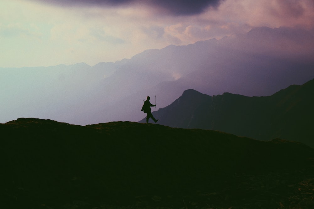 foto di silhouette di persona che cammina sulla montagna