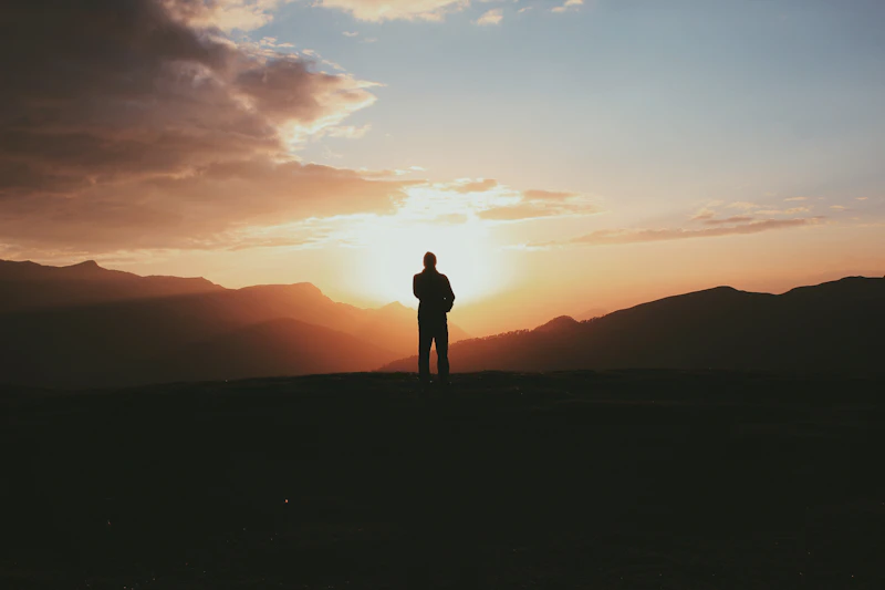 Silhouette photo of a UK sugar daddy standing on a mountain during golden hour