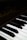 Close-up view of a piano keyboard showing several black and white keys. The focus is on the keys with the brand name faintly visible on the darker wooden surface above them.
