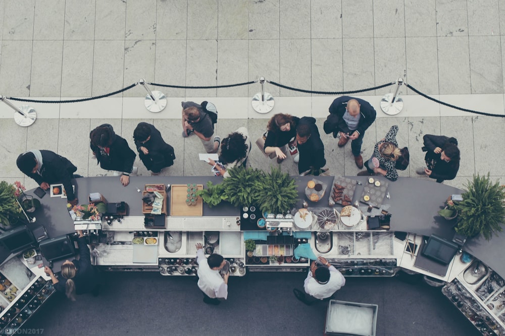 Fotografia com vista aérea de pessoas na fila do balcão de comida
