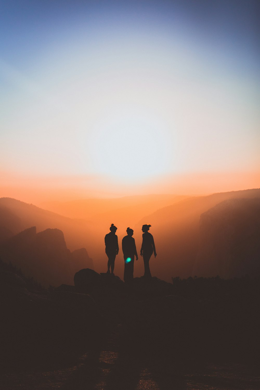 silhouette of three people up on mountain cliff