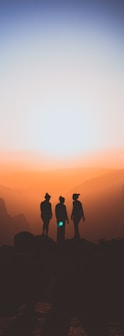 silhouette of three people up on mountain cliff