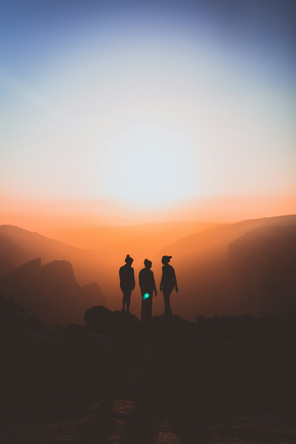 silueta de tres personas en el acantilado de la montaña