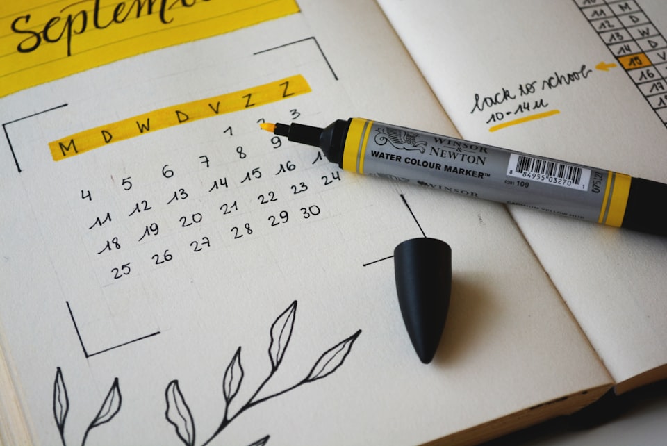 A yellow highlighter perched on a calendar drawn into a notebook.