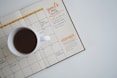 white ceramic mug with coffee on top of a planner