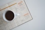 white ceramic mug with coffee on top of a planner
