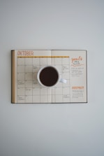 An overhead shot of a notebook with budgeting plans and a coffee cup beside it.