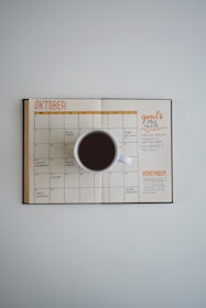 An overhead shot of a notebook with budgeting plans and a coffee cup beside it.