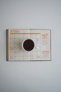A detailed monthly financial planner spread out on a wooden desk with a cup of coffee.