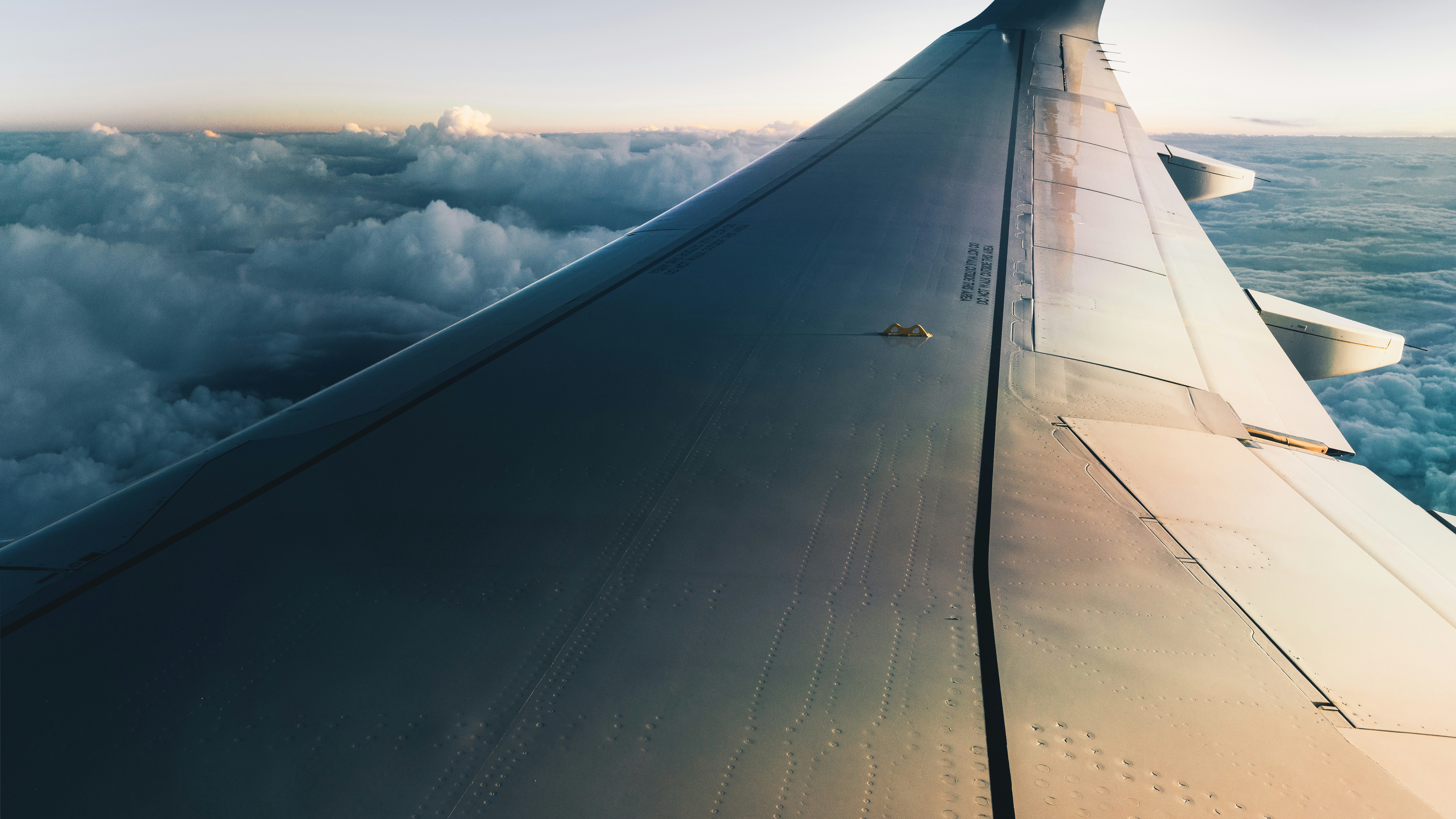 Aerial view of airplane wing over clouds during golden hour flight