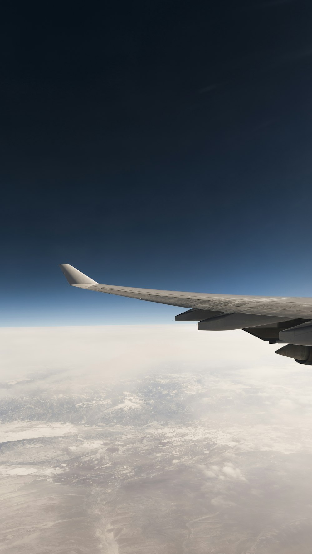 white airplane wing over white clouds