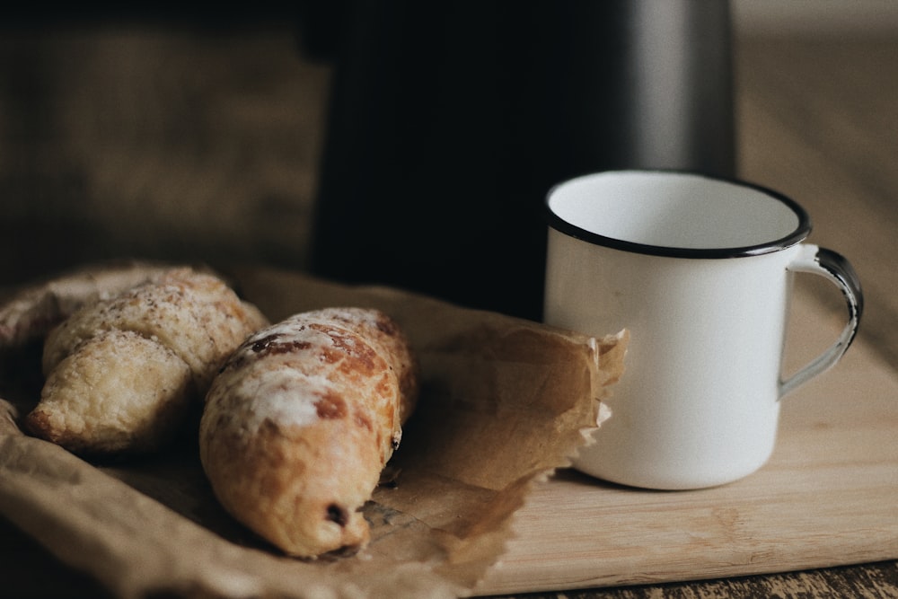 two breads on paper bag beside cup