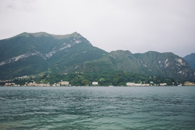 A serene lakeside view with smooth water and distant mountains.