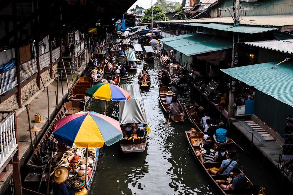 people riding boat in river near marketplace during daytime