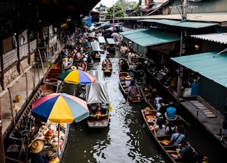 people riding boat in river near marketplace during daytime