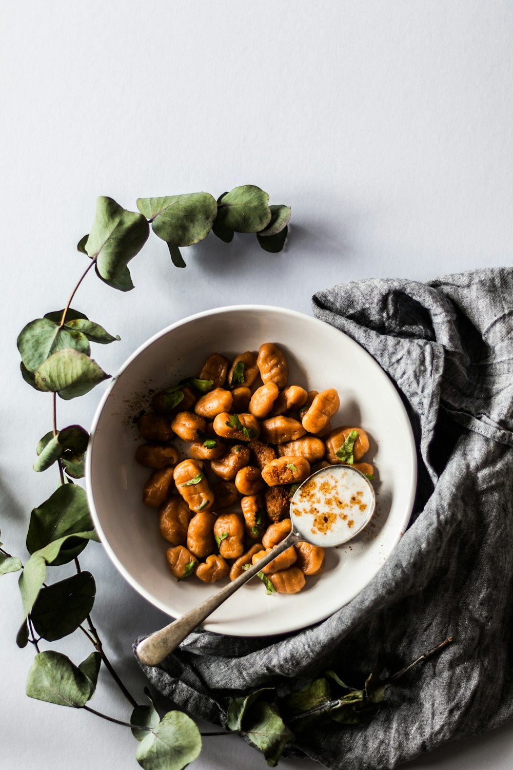 bowl of nuts with spoon beside green leaves