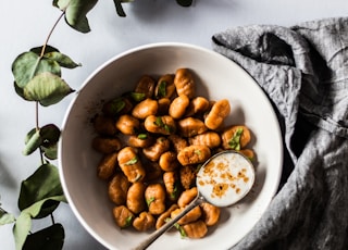 bowl of nuts with spoon beside green leaves