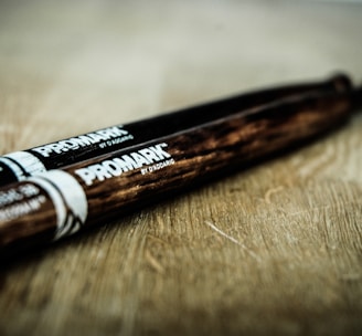close-up photography pair of black and brown Promark drum sticks