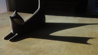 A sleek black cat stretching gracefully on a minimalist wooden floor