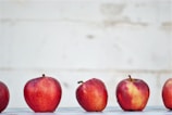 five red apples on white surface
