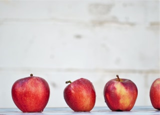 five red apples on white surface