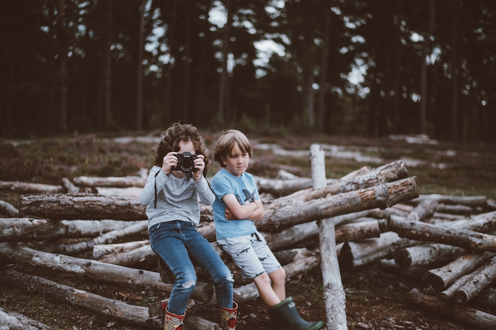 selective focus photography of boy and girl sitting on log