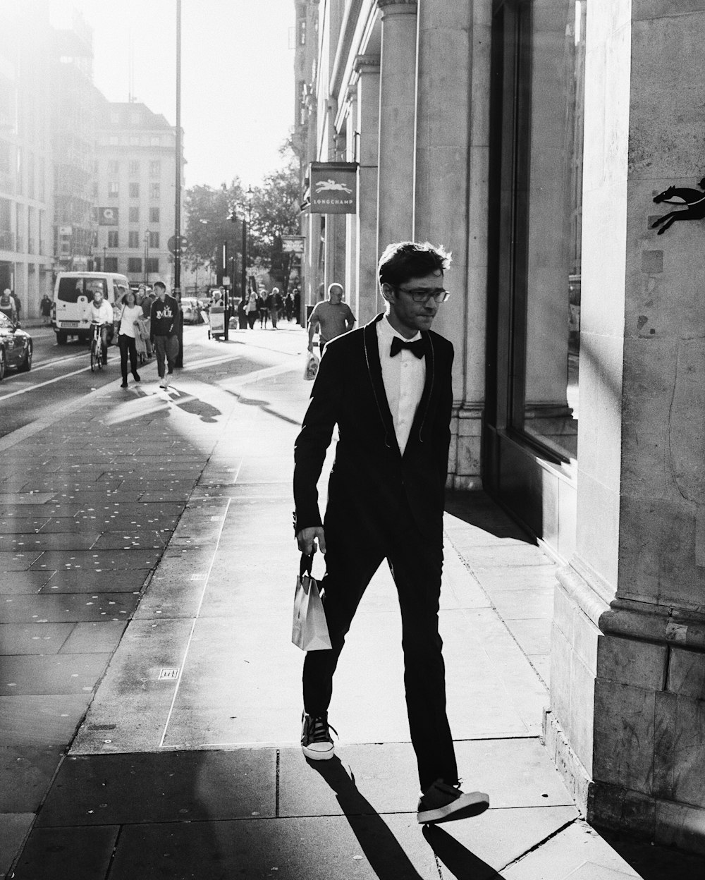 grayscale photo of man walking near concrete building