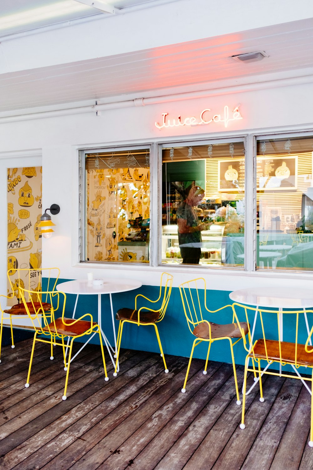 two round white metal tables with chairs beside wall