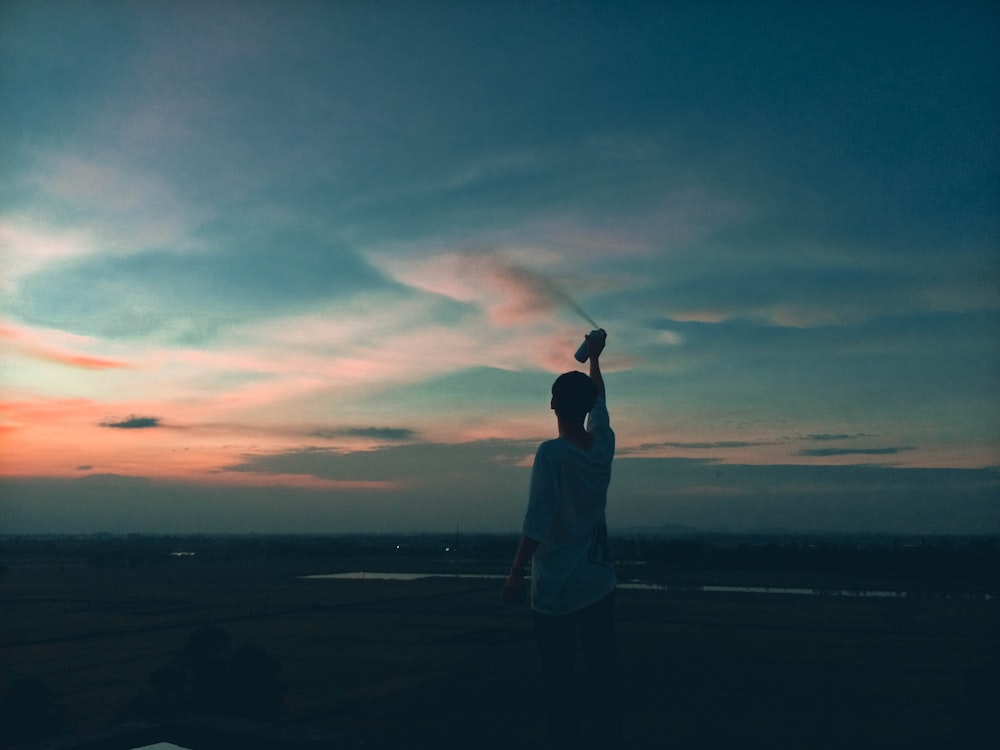 silhouette photograph of man spraying paint spray bottle