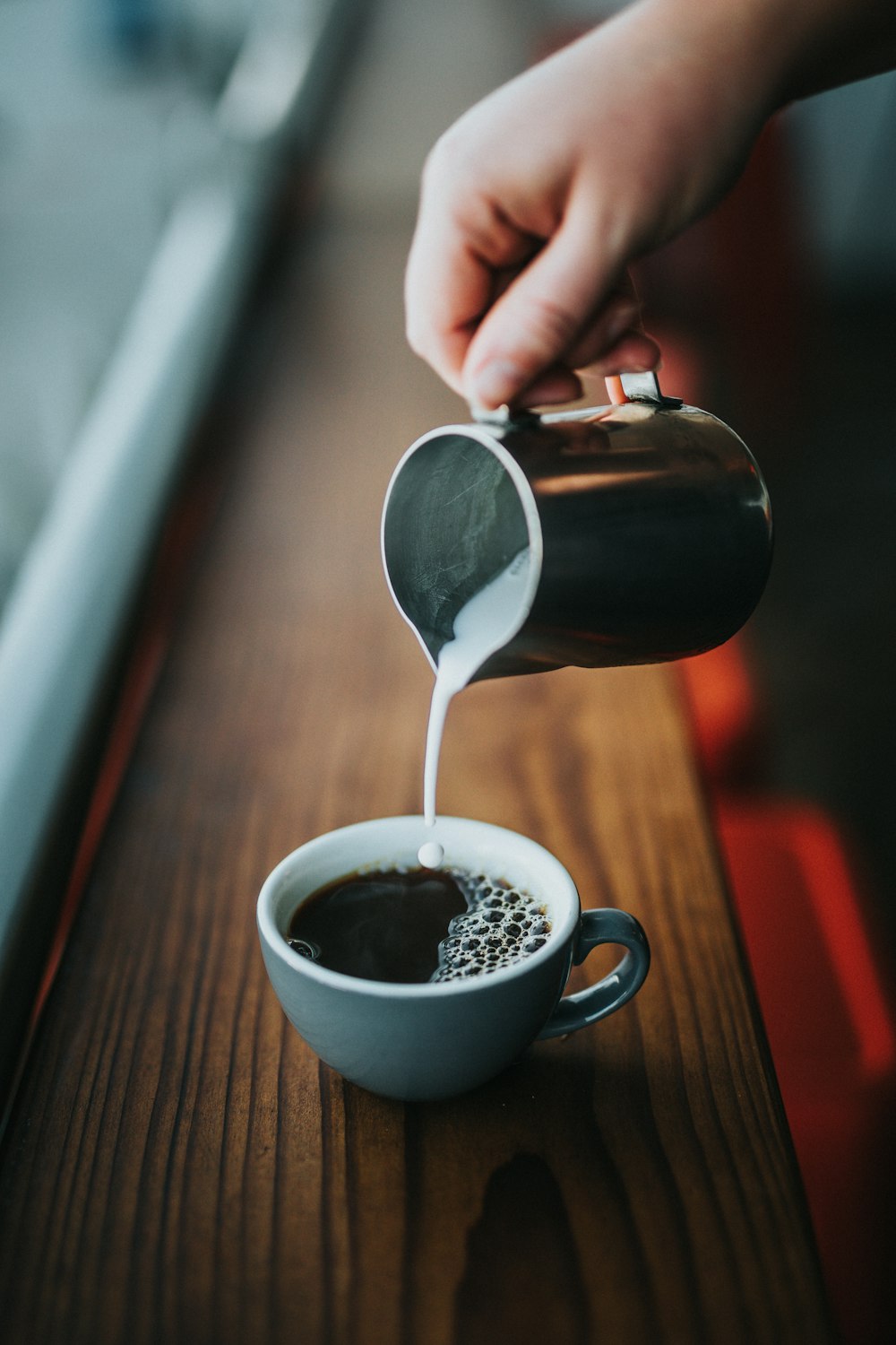 Person, die Milch auf Kaffee gießt