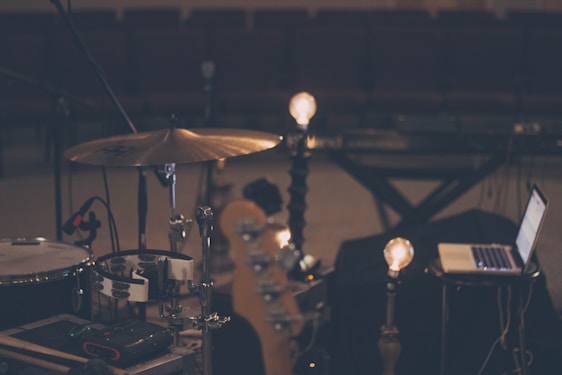 A warm studio scene with musicians and writers collaborating, surrounded by instruments, notebooks, and soft natural light.