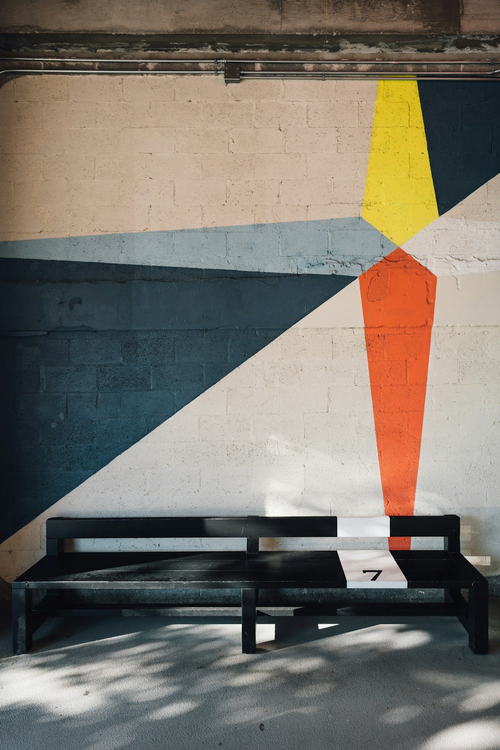 black wooden bench near white, blue, and orange painted wall