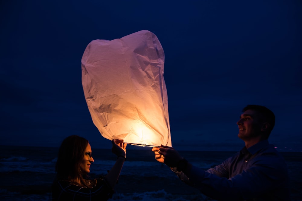 man and woman holding white sky lantern