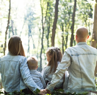 Family - man and woman holding hands together with boy and girl looking at green trees during day