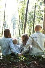 Family - man and woman holding hands together with boy and girl looking at green trees during day