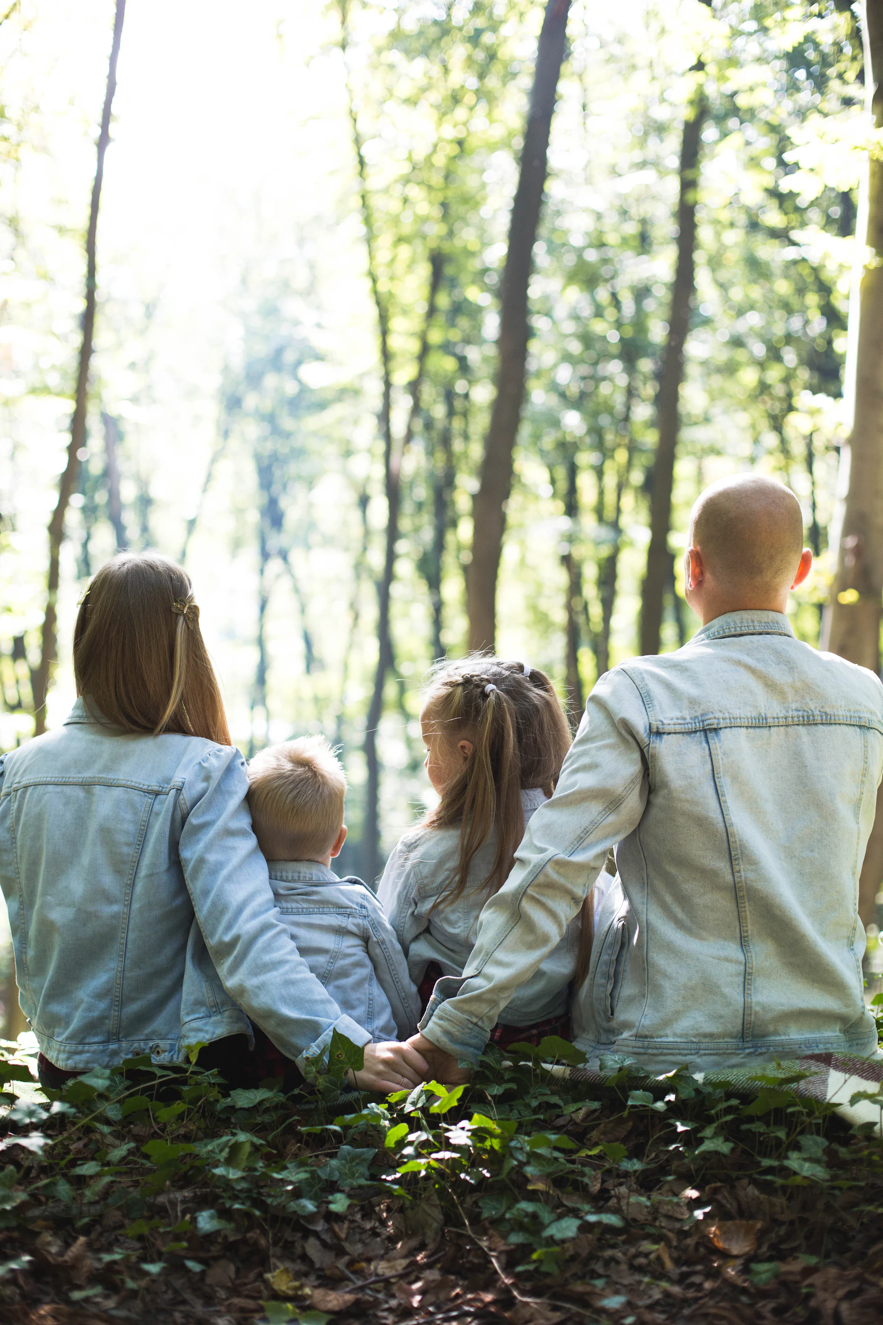 Parents holding hands with their children outside on a sunny day