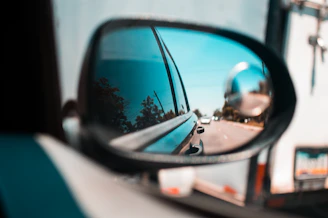 A learner confidently checking mirrors before making a turn on a sunny day.