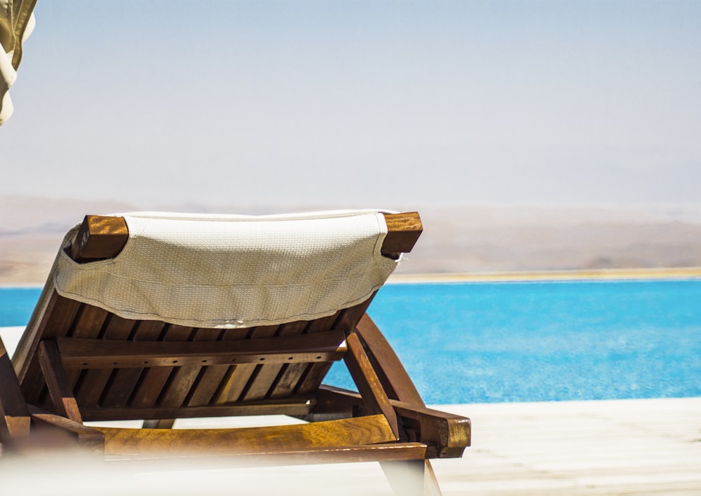 brown wooden lounger on seashore facing ocean