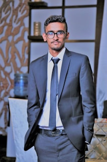 A stylish man wearing a formal business suit at an office setting.