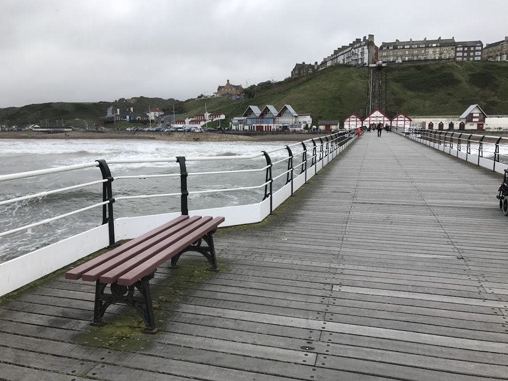 brown bench on pathway near body of water