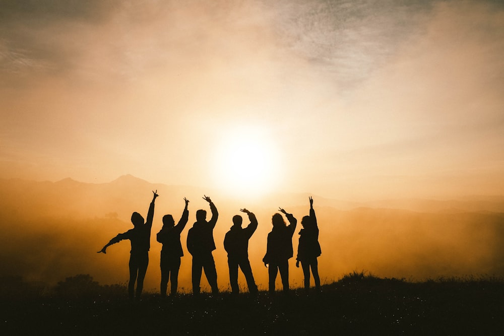 Silhouettenfoto von sechs Personen auf dem Gipfel des Berges