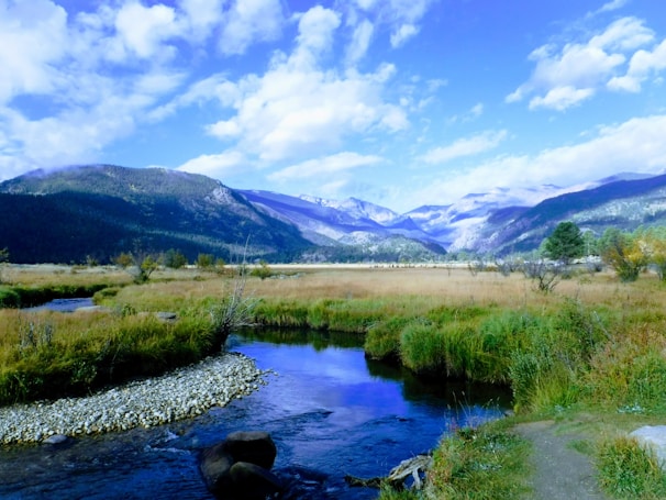 A serene landscape of the farm with mountains in the background and a clear stream flowing.