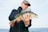 man holding grey fish with ocean background