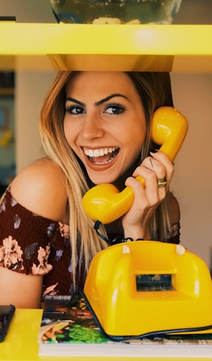 woman holding yellow rotary telephone