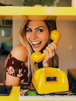woman holding yellow rotary telephone