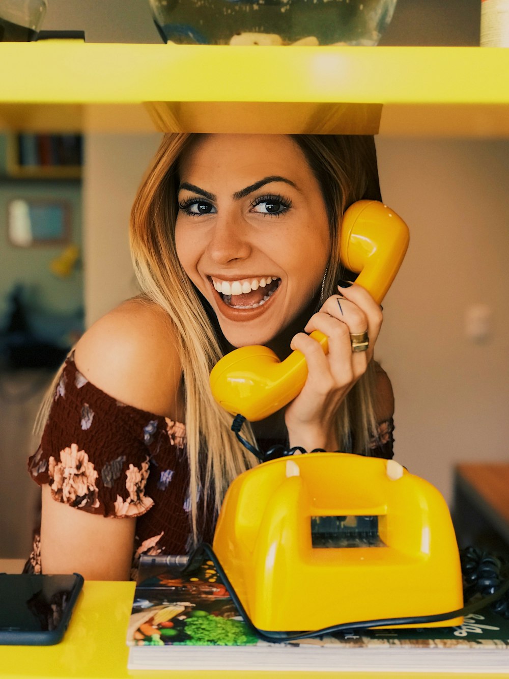 Femme tenant un téléphone à cadran jaune