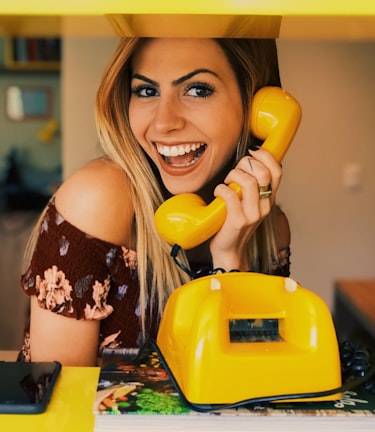 woman holding yellow rotary telephone