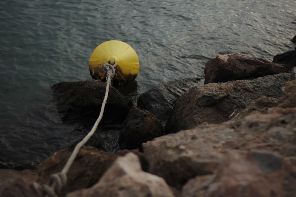 yellow buoy beside rock