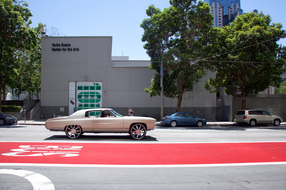 silver coupe in front of building