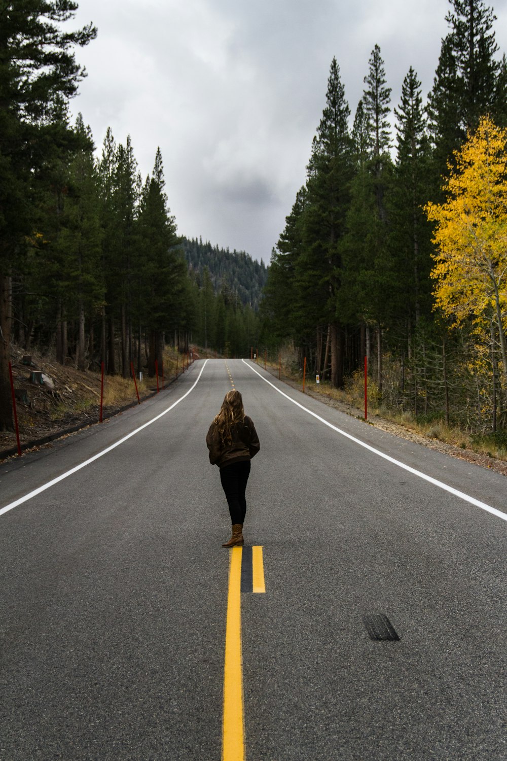 woman wearing black jacket and black pants standing on roadway